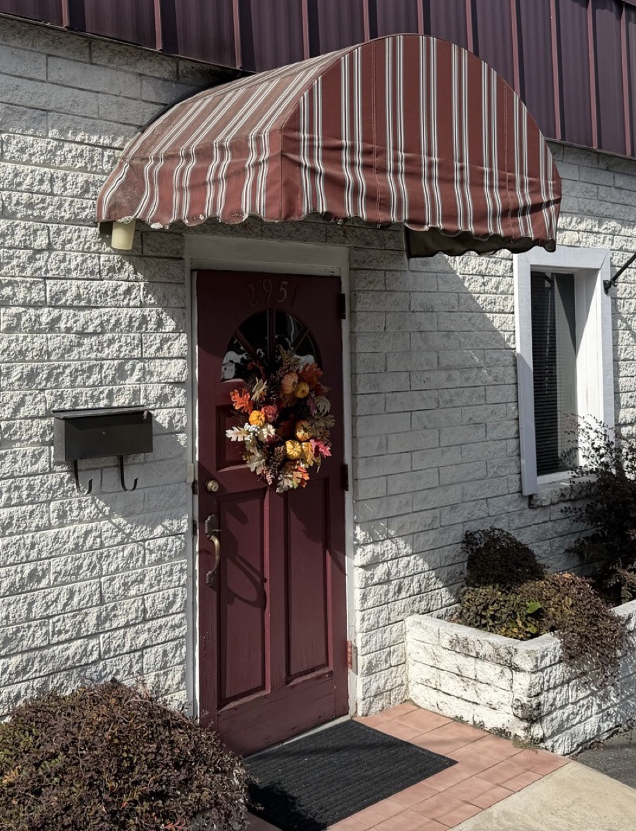 The maroon front door of Hair Mechanics under a striped awning